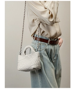 Detail shot of white woven leather mini bag featuring silver-black metal chain strap
