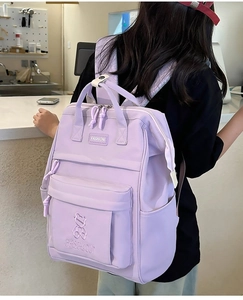 Detail of purple nylon school backpack with multiple compartments and embroidery on back