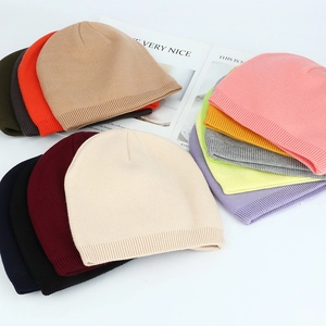 Flat lay of colorful winter knitted beanies in various shades including pink grey and green