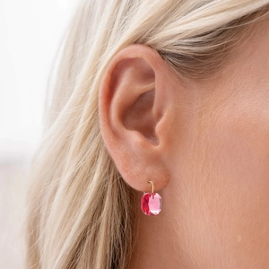 Dettaglio di un orecchino di lusso con cristallo rosa e gancio d'oro su una modella