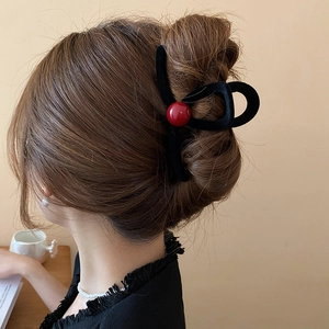 Detail of red bead accents on black flocked claw clip for hair styling in use