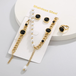 Detail of gold stainless steel jewelry set featuring black gems and white pearls on stand
