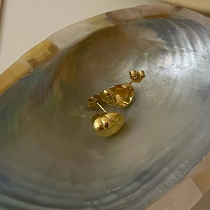 Polished gold croissant heart earrings resting inside an iridescent seashell detail