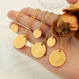 Detail of gold coin pendants featuring Elizabeth II portrait on titanium steel necklaces