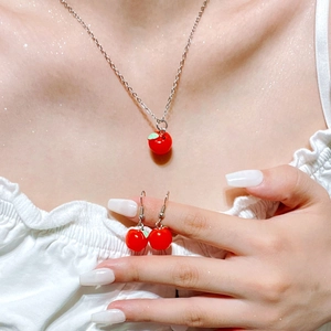 Close-up of sweet red cherry necklace and matching earrings set worn by a model