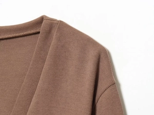 Macro view of brown knit cardigan showing detailed ribbed texture and shoulder seam work