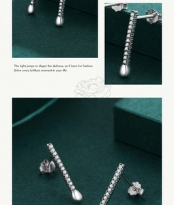 Detail of silver drop earrings with shimmering crystals on a dark green background