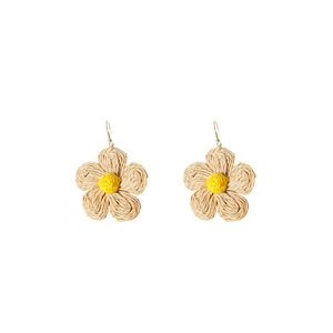 Detail of handmade raffia flower earrings with beige petals and yellow centers on gold hooks
