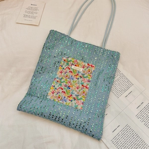 Detail of blue sequined tote bag with colorful floral pocket and vintage newspaper background