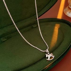 Primo piano di una collana con ciondolo a cavallo a dondolo in scatola di velluto verde