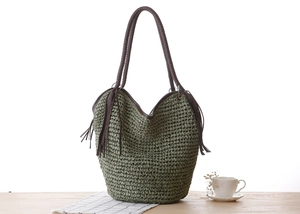 Détail du sac en corde de papier vert olive avec anses en cuir et pompons décoratifs