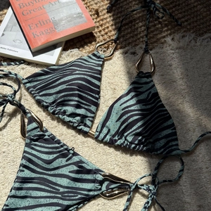 Detail of zebra print bikini with gold hardware on luxury textured resort background