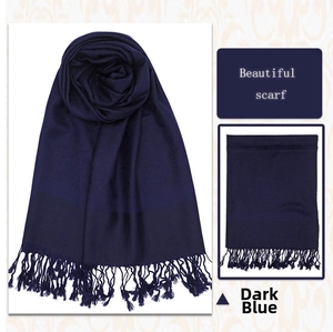 Detail view of navy blue luxury scarf showing jacquard texture and tassel fringe