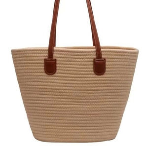 Large beige woven cotton rope tote bag with brown leather handles on white background