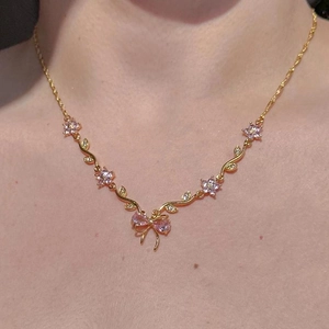 Detailansicht der goldene Pfirsichblütenkette mit rosa Edelsteinschleife am Hals
