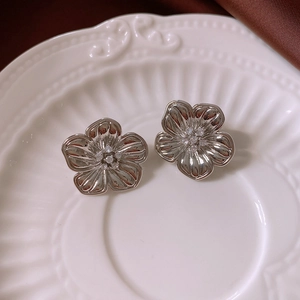Detailed macro view of silver flower stud earrings on a vintage ceramic texture