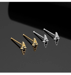 Close-up of S925 silver alphabet A nose studs in gold and silver on black surface