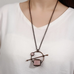 Vintage long necklace with rose quartz pendant on a bronze frame worn by a model