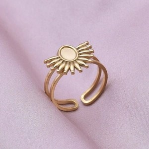 Detailed view of an adjustable golden sunburst ring on elegant purple silk background