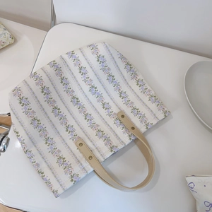 Close-up of floral tote bag with purple flowers and synthetic leather handles