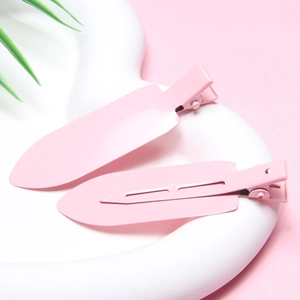 Close-up of two pink metal creaseless hair clips on a white heart-shaped ceramic tray