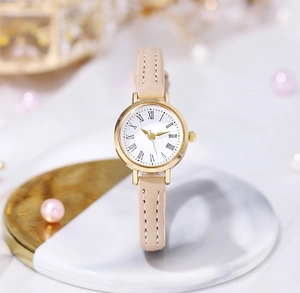Close-up of elegant gold watch with white Roman dial and beige slim leather strap
