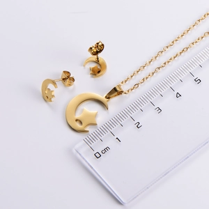 Macro shot of gold moon and star jewelry set next to a ruler showing pendant dimensions