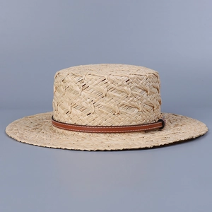 Detail shot of hand-woven raffia texture and brown leather strap on a boater sun hat