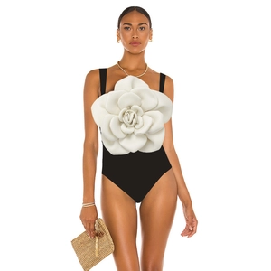 Detail of elegant black one-piece swimsuit featuring a large white 3D camellia flower