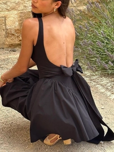 Detail of a backless black dress featuring a large bow tie and ruffled skirt hem