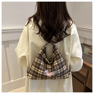 Brown checkered tote bag featuring a cute dog embroidery shown on a female model shoulder