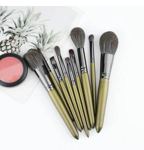 Macro shot of 10 olive green makeup brushes with taupe bristles on a white background