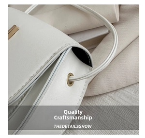 Detail shot of white leather saddle bag showing fine stitching and gold hardware