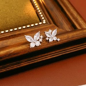Gros plan de boucles d'oreilles papillon en argent avec zircons sur cuir vintage