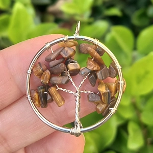 Close-up of handmade tree of life pendant with silver wire and brown tiger eye stones