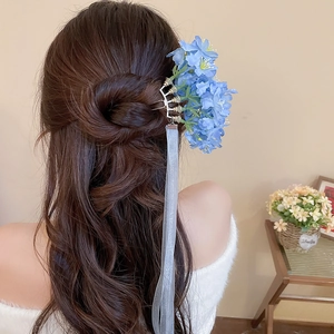Rear view of a blue fabric flower hair pin with long flowing translucent ribbons