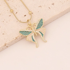 Golden butterfly necklace with green enamel wings and zircon pendant on stone