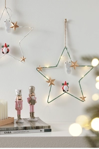 Detail of star-shaped Christmas LED ornament with a festive gnome on warm lit iron frame