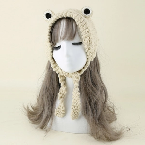 Detail of hand-knitted beige frog earflap hat with thick yarn texture and long ties