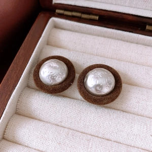 Detailed macro view of vintage round earrings with silver hammer texture and brown velvet