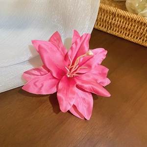 Detail of pink fabric lily hair clip with realistic petals on a wooden surface