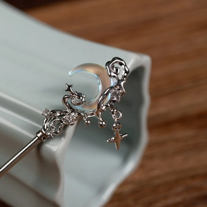 Macro view of silver crescent moon hair stick with glittering rhinestones and star charm