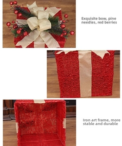 Detail view of red Christmas gift box with burlap bow, pine needles and iron frame