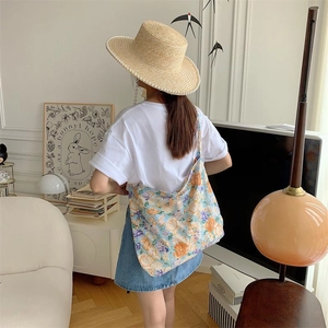 Lifestyle shot of a large floral canvas tote bag in light blue with orange flower patterns