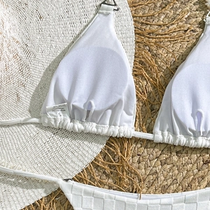 Detail of white bikini with checkerboard towel fabric texture and pearl string accents