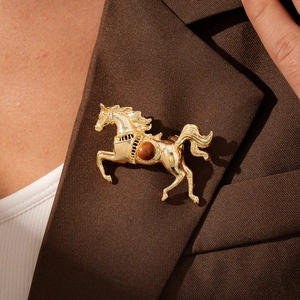 Detail of a gold horse brooch with brown gemstone pinned on a brown suit lapel