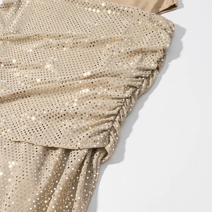 Détail des paillettes dorées champagne et des fronces latérales sur la robe de femme