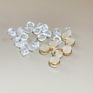 Macro shot of transparent silicone earring backs with gold metal base detail on leather