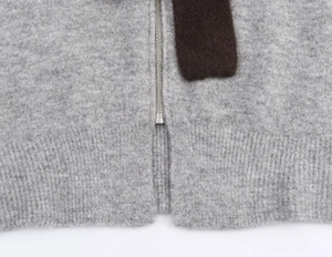 Detail of grey knitted sweater with silver metal zipper and ribbed hem finish