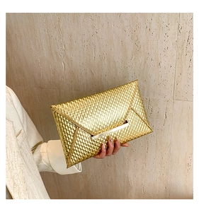 Detail of gold envelope clutch bag with snakeskin texture and metal closure bar